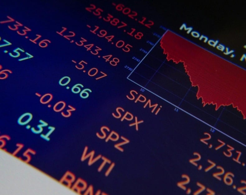 Stock market dashboard with red downward graph and colorful numeric tickers indicating mixed financial data on-screen