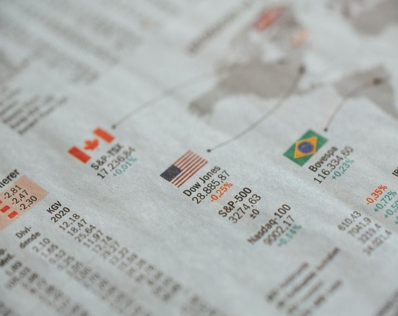 Close-up of a financial page showing Dow Jones with an American flag graphic and other global stock indicators and numbers.
