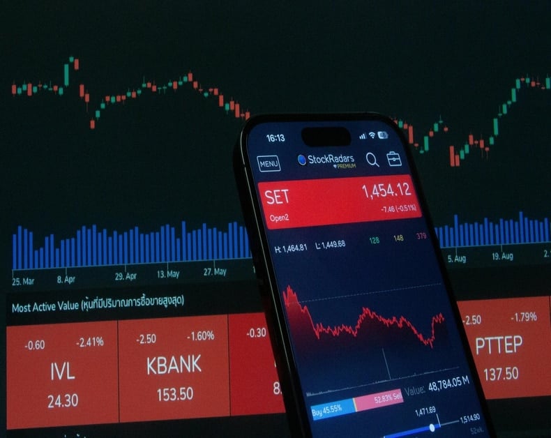 Smartphone showing a stock trading app over a blue-red market chart background with SET index value visible (1,454.12) and a red line graph in blue-lit UI.