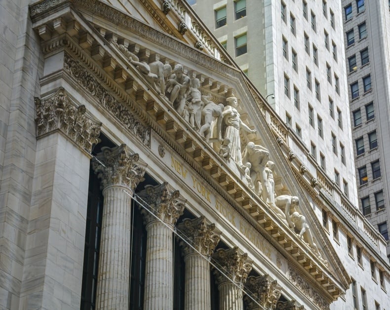 Facade of the New York Stock Exchange with ornate pediment and sculpted figures atop the entrance.